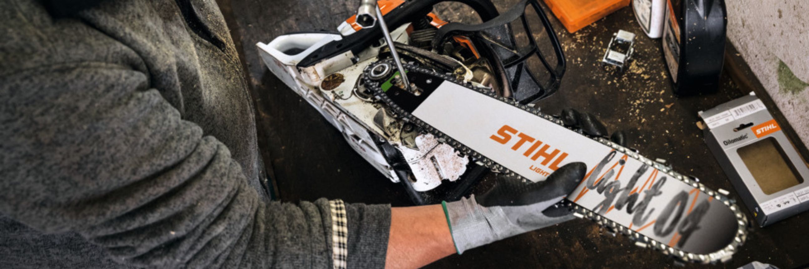 Person entfernt Schraube an Kettensäge, um die Motorsäge zu reinigen